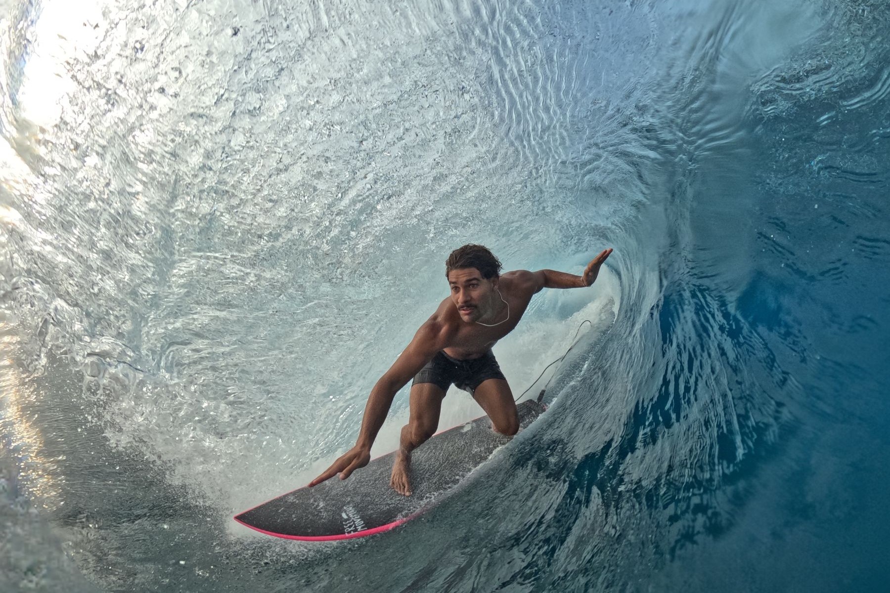 Surfer pointing the way inside a glassy barrel