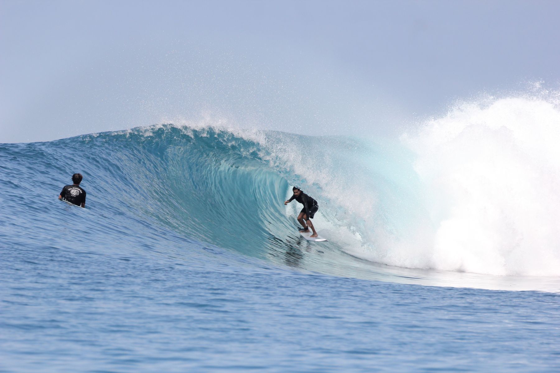 Surfer in the barrel as another paddles into position