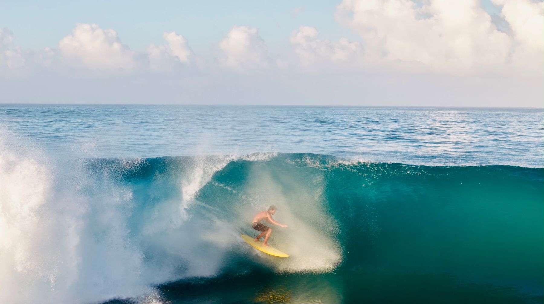 Surfer deep in a barrel on a yellow board