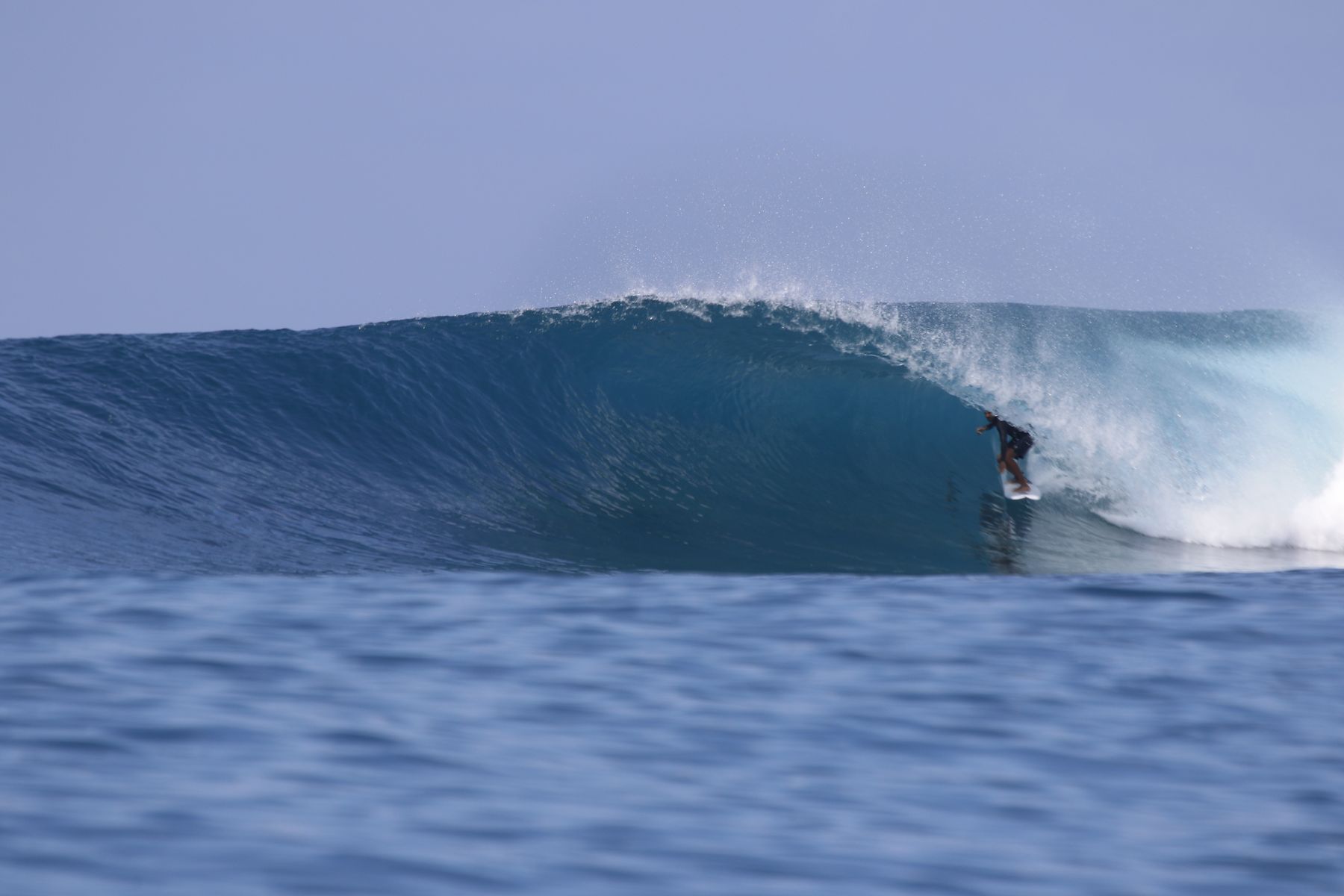 Surfer inside a clean blue barrel