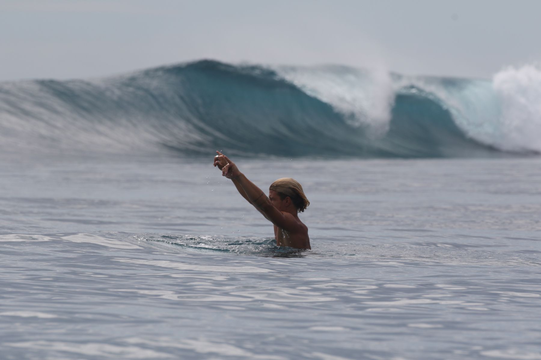 Surfer signaling for a wave, swell breaking behind